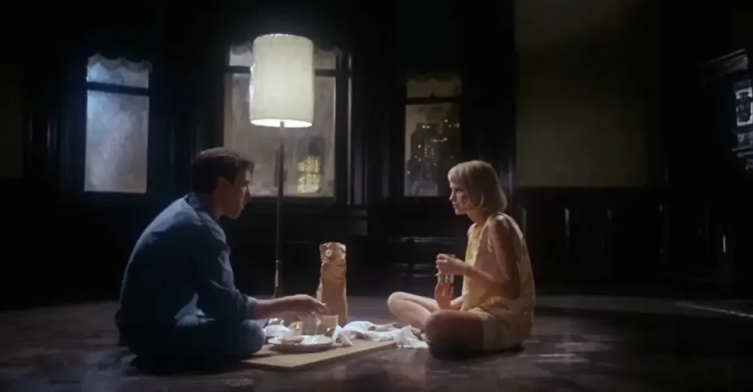 John Cassavetes y Mía Farrow cenan en su piso vacío recién mudados. 