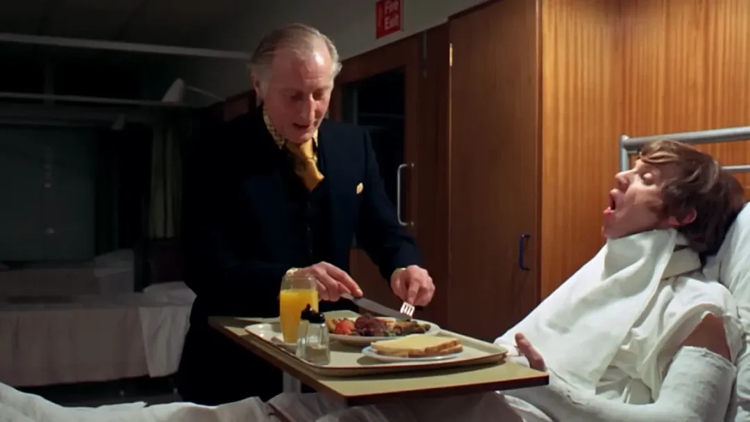 La corbata naranja del Ministro y los tonos madera mientras da de comer a Alex, acusan al sistema de alimentar a la bestia